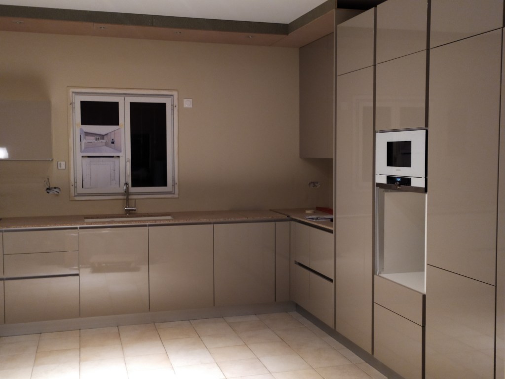 Cuisine sur mesure aux façades beige clair avec rangements intégrés et plan de travail.