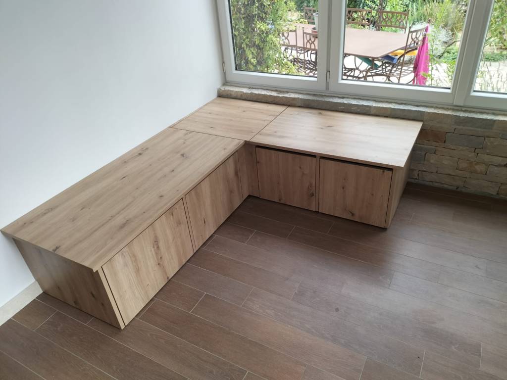 Banquette de rangement sur mesure en bois, intégrée sous une fenêtre.