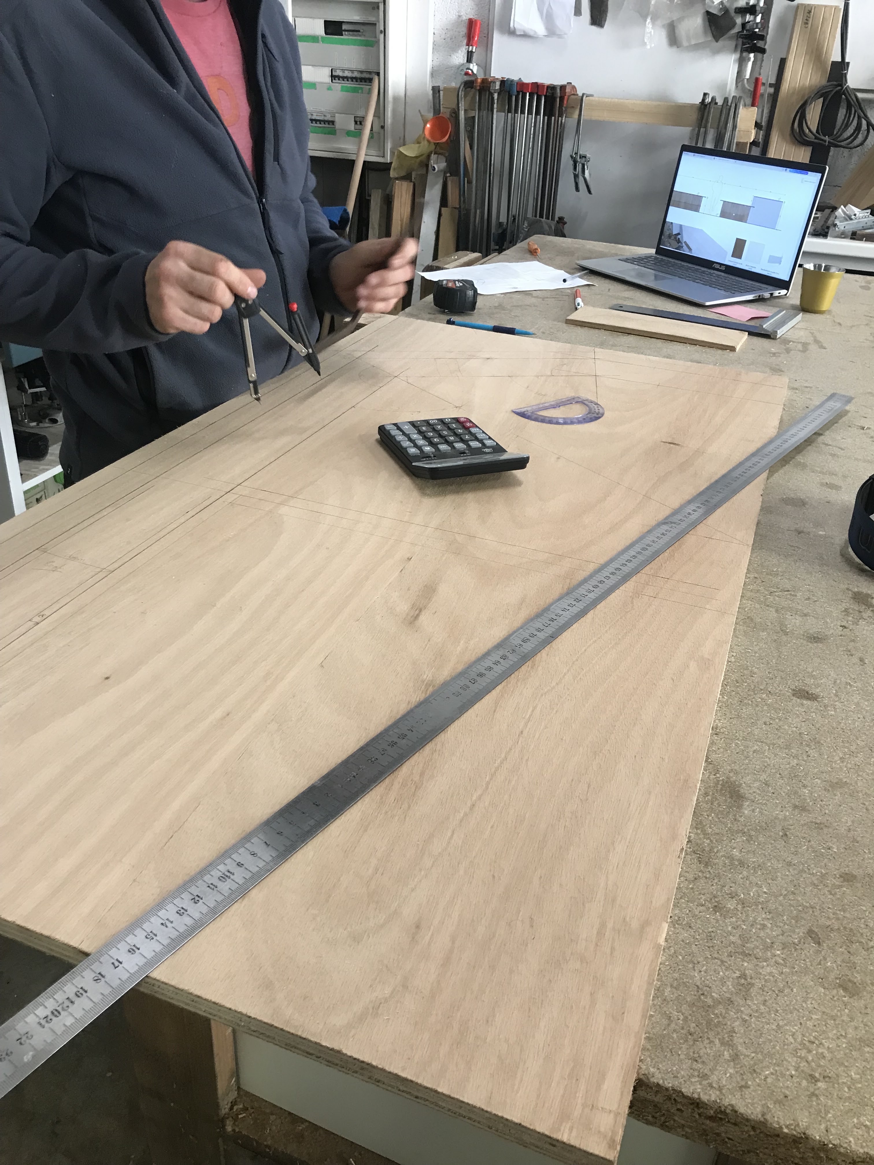 Prise de mesures tracages sur un panneau en bois lors de la fabrication en atelier.