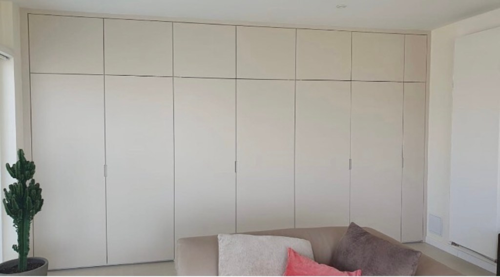 Placards muraux sur mesure toute hauteur avec façades blanches et mdf lignes épurées.